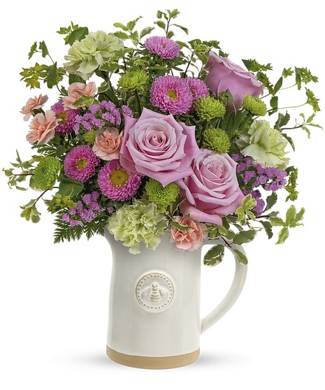 pink and green spring floral arrangement in pitcher