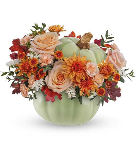 An arrangement of pinks and oranges in a light green pumpkin shaped container
